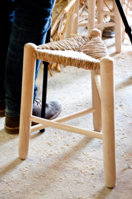 Taburete artesanal de tres patas con asiento de enea.